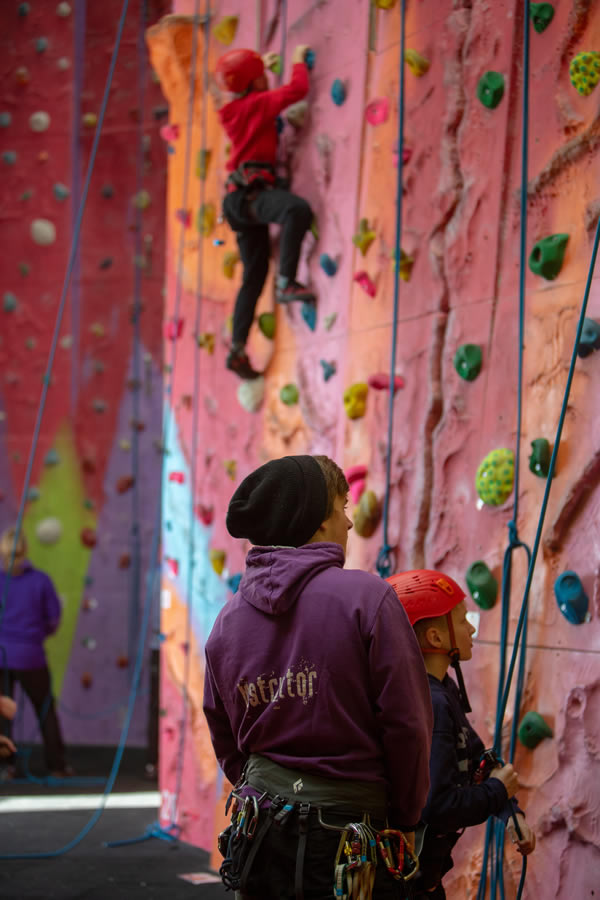 Instructor assists young people climbing