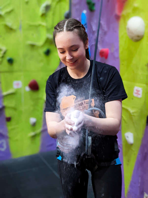 young person chalks hands for climbing